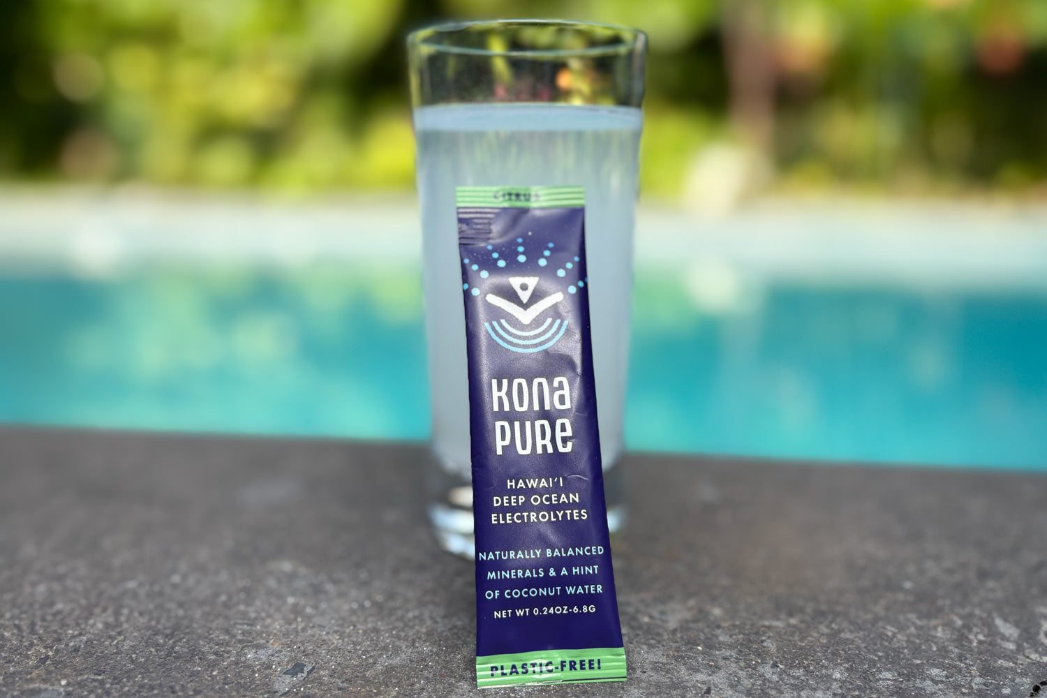 Kona Pure Deep Ocean Electrolytes with a glass of water on a blurred pool background