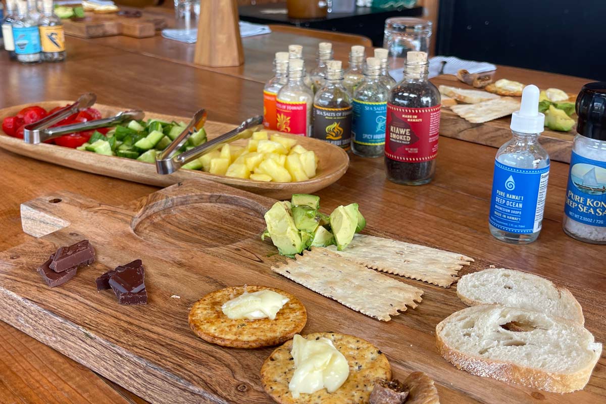 Assorted food items on a wooden board with bottles of salt in the background