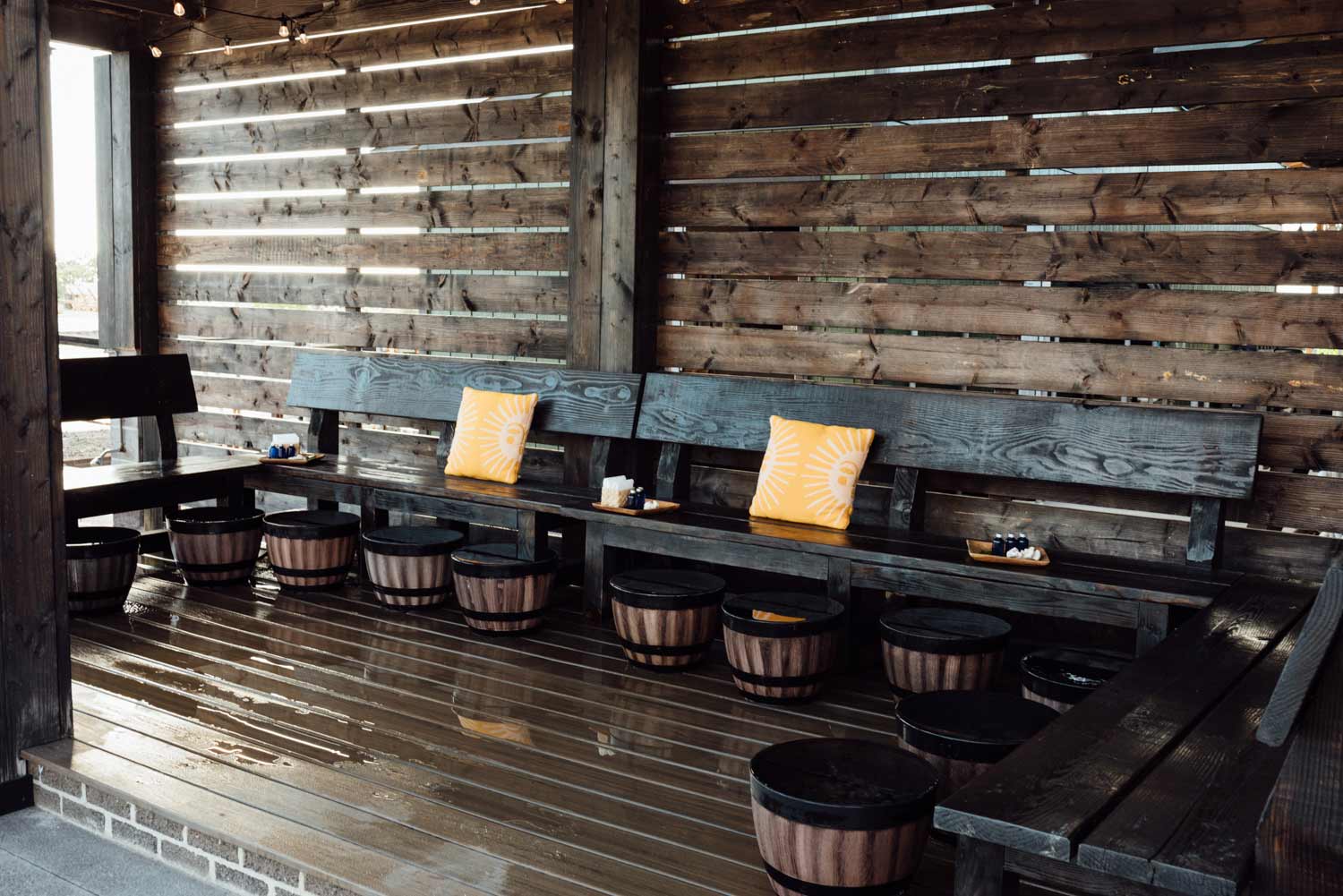 Foot Soak cabana with a wooden bench, cushions and foot soaking tubs in a rustic outdoor setting