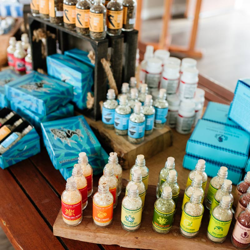 Table with assorted salt bottles and gift boxes on a wooden surface