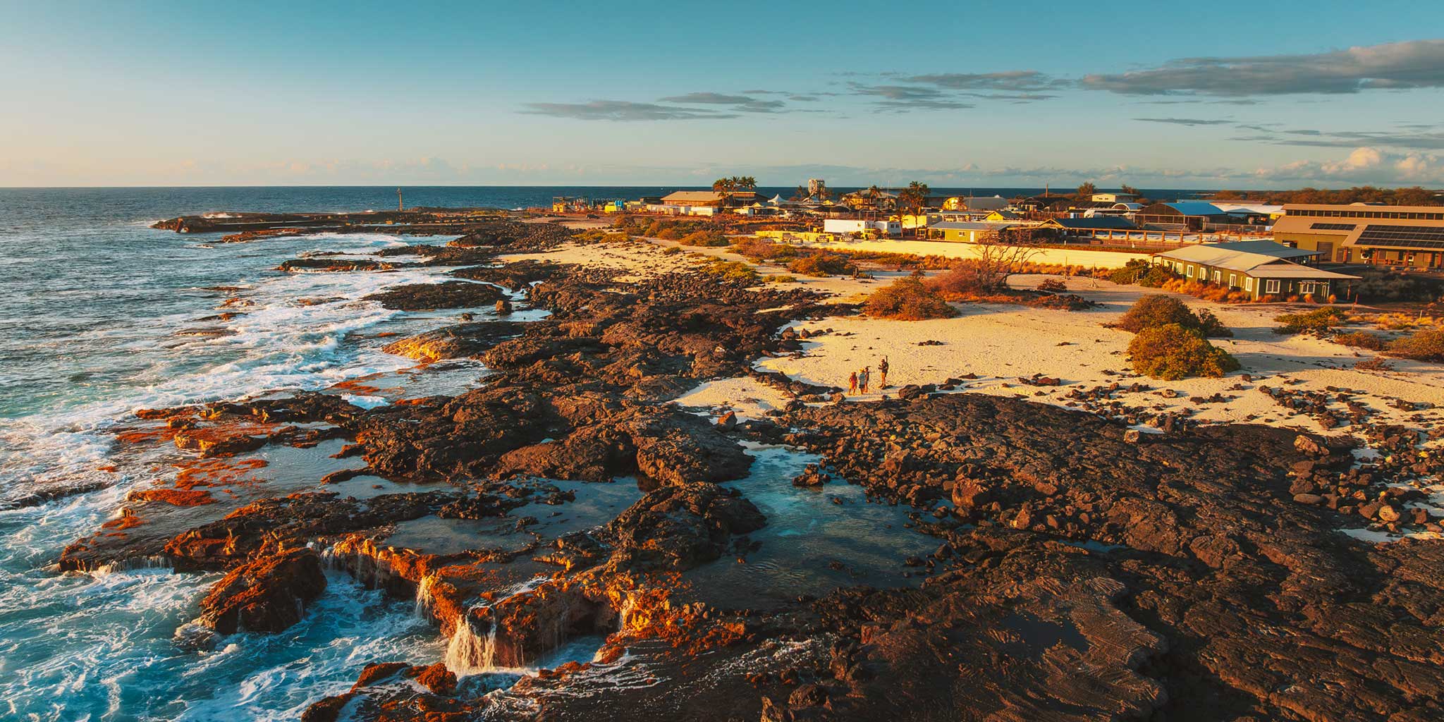 Coastal landscape with rocky shore and buildings in the distance.