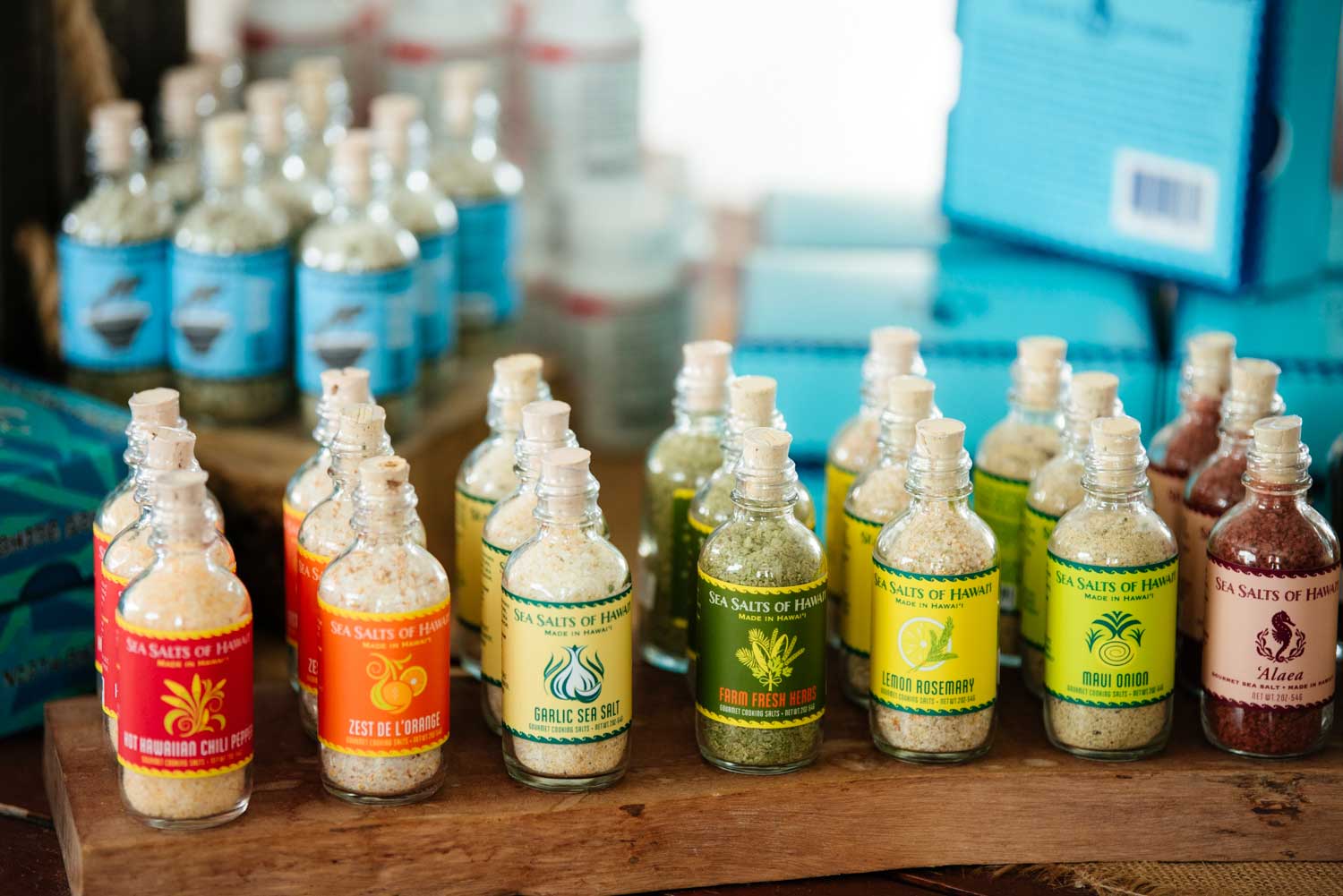 Various bottles of Hawaiian Sea Salt on display in the Farm Store on a wooden surface with a blurred background.