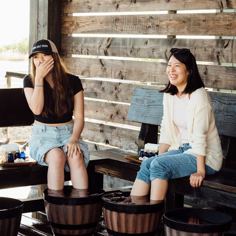 Two women sitting with their feet in the Deep Ocean Water Foot Soak.